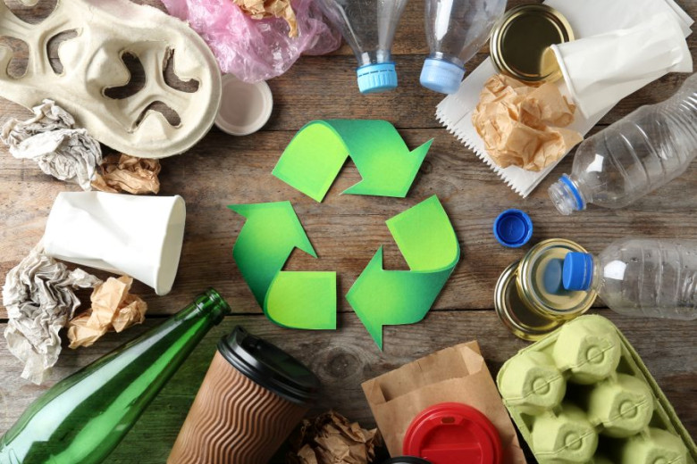 Recycling symbol and different garbage on wooden background.
