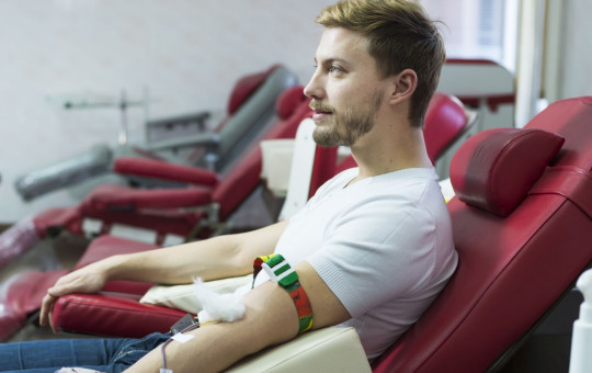 Men lying in a hospital giving a blooddonation-naslovna