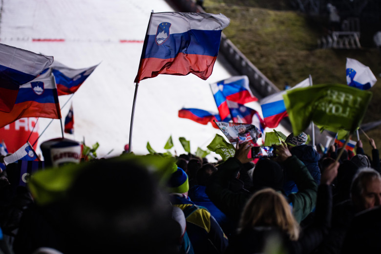 Spectators wave flags at the ski jumping hill.
