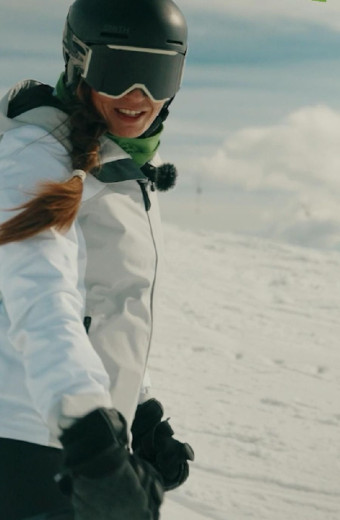 A female skier wearing a helmet and a ski suit, with her face turned toward the camera.