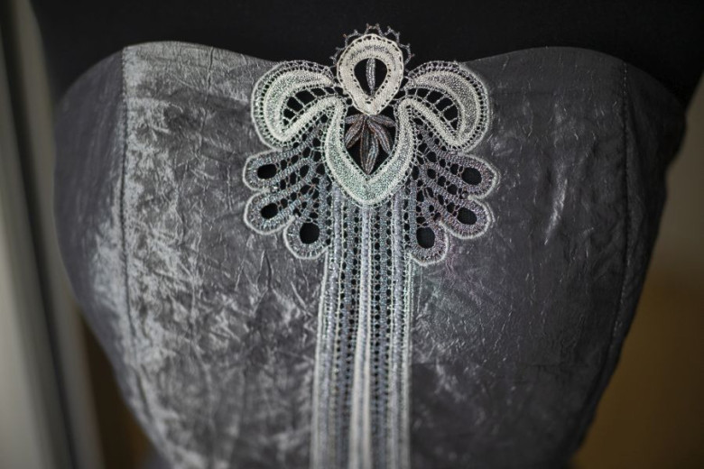 The upper part of a beautiful silver dress on a mannequin, with Idrian lace in the middle.