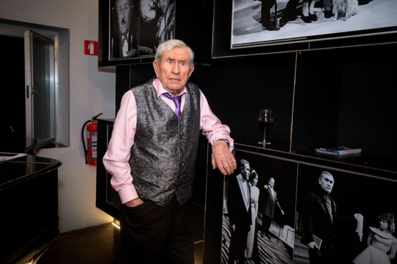 Igralec Jurij Souček stoji ob svojih fotografijah na steni