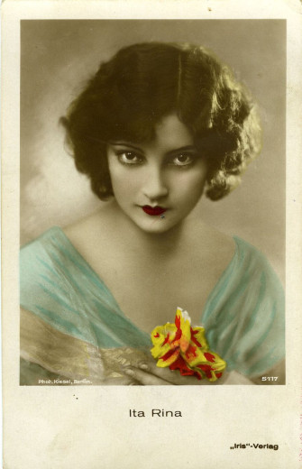 Vintage portrait of a woman with dark wavy hair and red lips, dressed in a sheer teal wrap, holding a yellow and red flower. Elegant and mysterious tone.