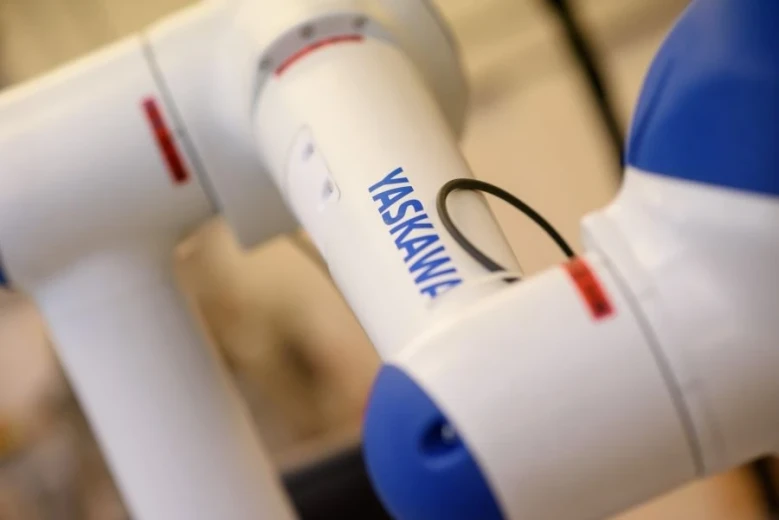 A close-up of a white and blue Yaskawa robot.