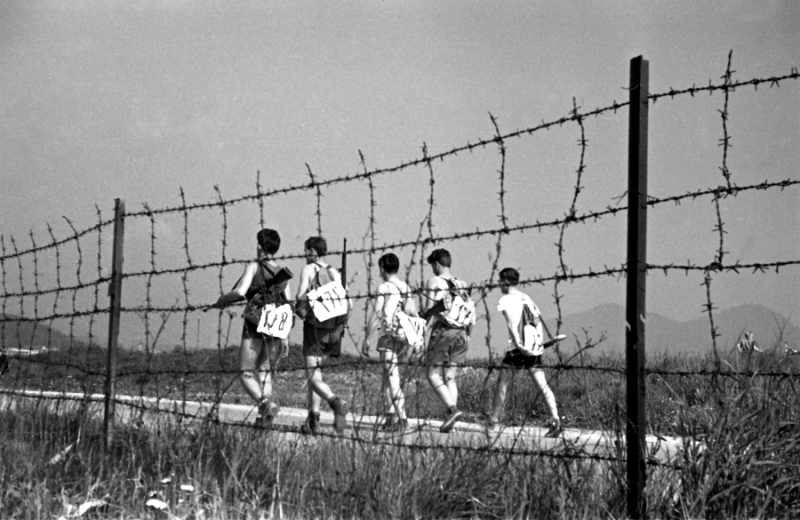 A group or young man running along a barbed wire.