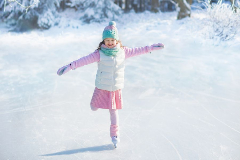 A girl in a pink is learning to skate on the frozen lake