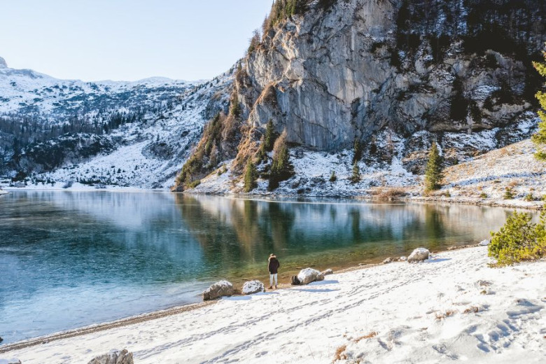 A woman is standing at the bank of the Lake Krn in the winter time