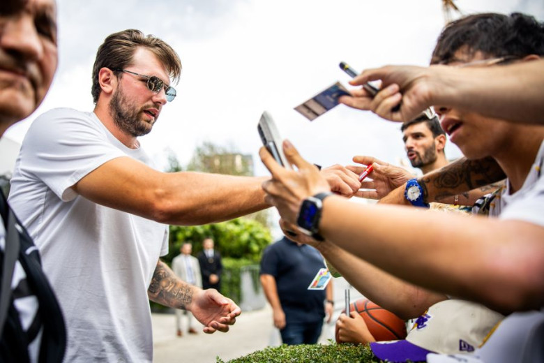 Luka Dončić in sunglasses signs autographs for enthusiastic fans.