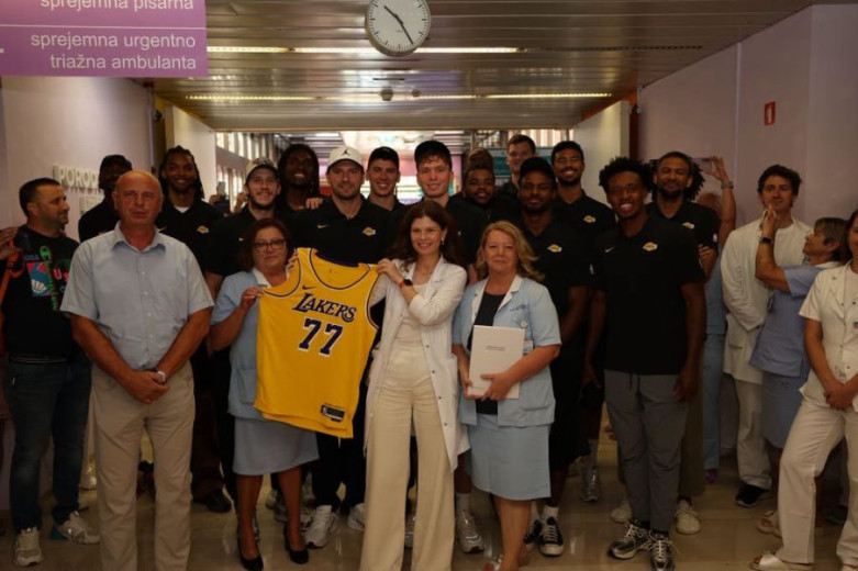 Group photo of the Los Angeles Lakers team with the staff of Ljubljana Maternity Hospital, holding Luka Dončić’s No. 77 jersey.