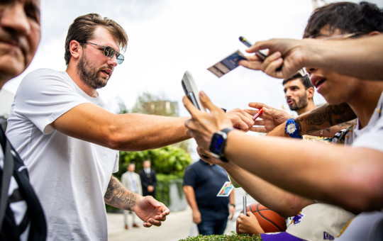 Luka Dončić in sunglasses signs autographs for enthusiastic fans.