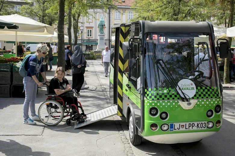 With the assistance of a companion, a wheelchair user boards the electric Kavalir vehicle via an accessible ramp.
