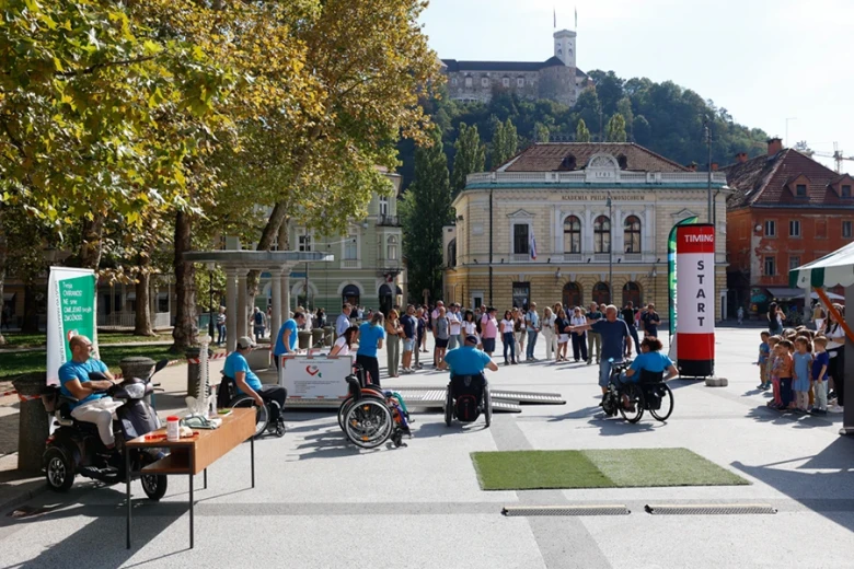 People take part in an event in a city square, where they test navigating various obstacles in wheelchairs.