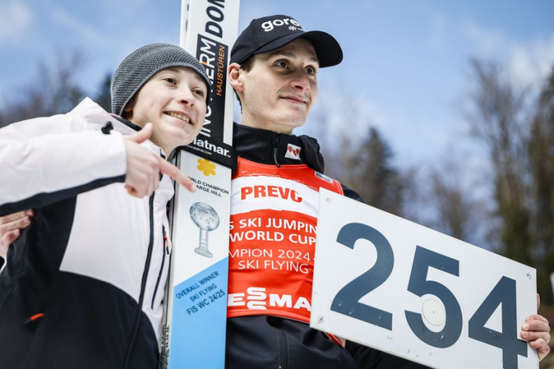 Domen Prevc is holding a sheet with the number 254, and next to him stands his sister Nika, smiling and pointing at the number.