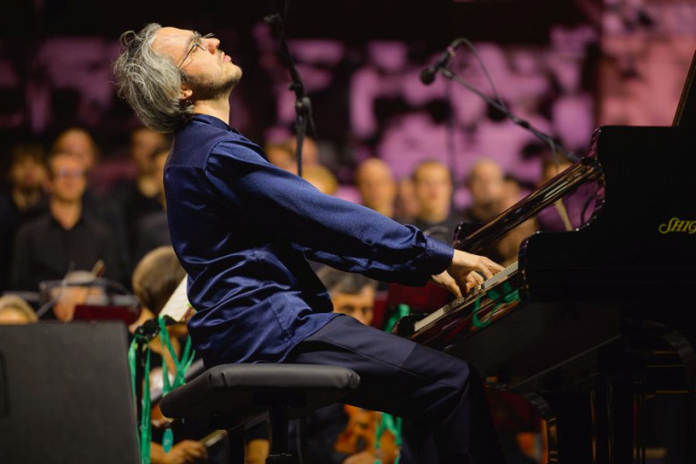 Pianist Aleksander Gadžijev during a recital on stage with audience in the backround.