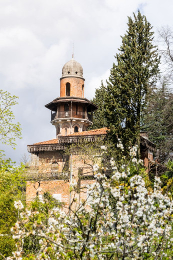 Brick building with dome amidst blooming trees and tall pines.