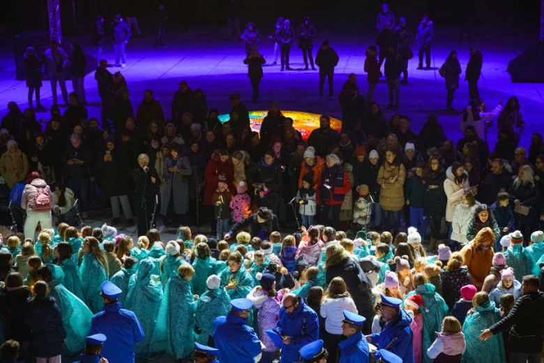 A large crowd gathered at night, to listen to a performance by childrens choir. 