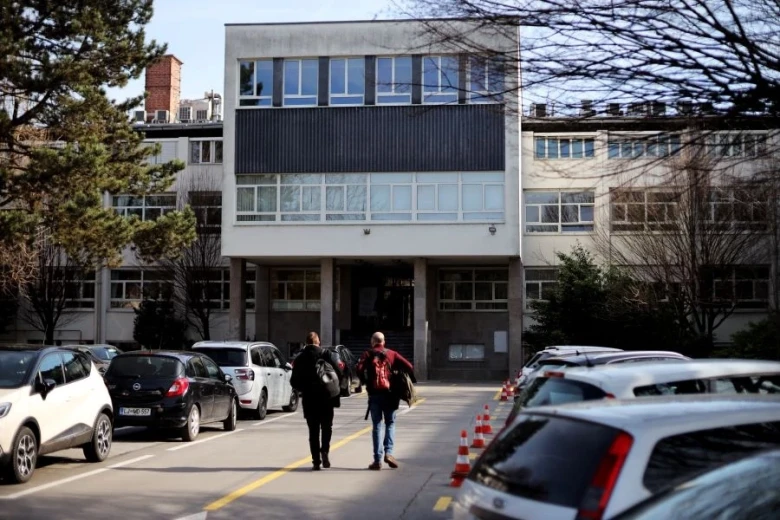 Dve osebi hodita s parkirišča proti stavbi Instituta Jožef Stefan.