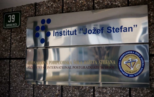 A metallic board on the facade of a building with an inscription Institut Jožef Stefan.