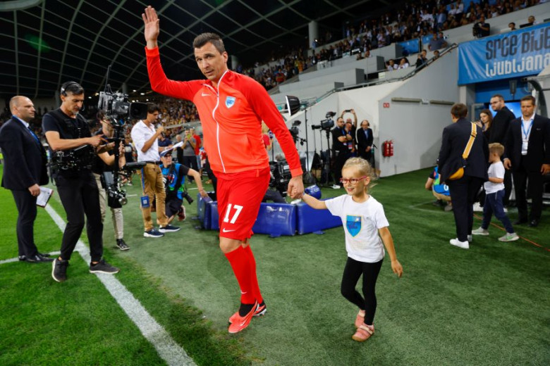 A football player arrives at the stadium. He is holding a girl by the hand.