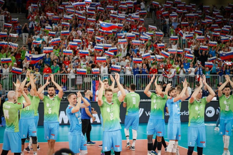 Joy of volleyball players after victory, fans with flags in the stands.
