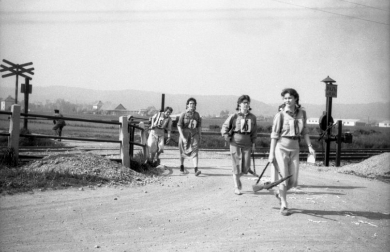 A group of young women wearing guns crossing a railway path