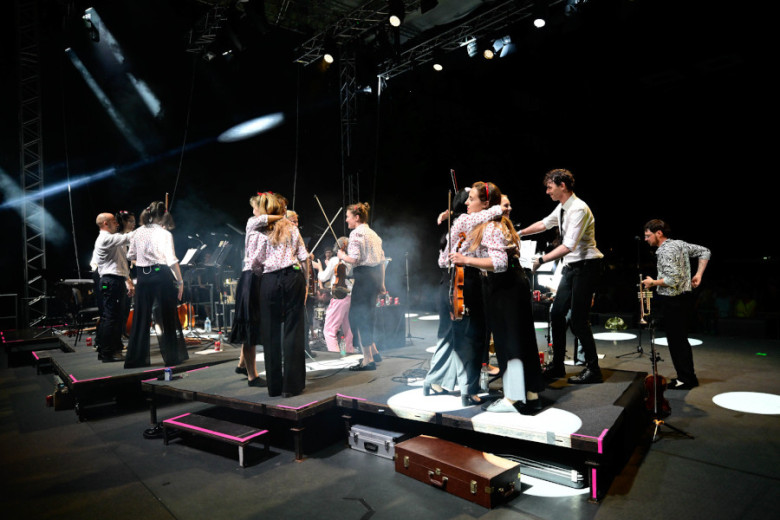 Musicians on the stage are celebrating and hugging with eachother.