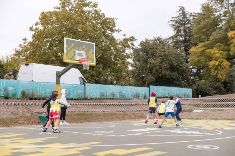 Boys are throwing a ball at a basketball hoop.