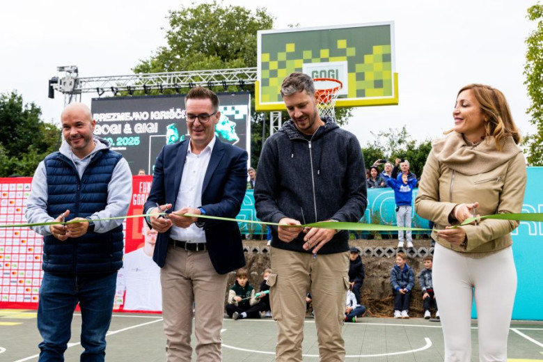 Three men and one woman are cutting a ribbon on a basketball court.