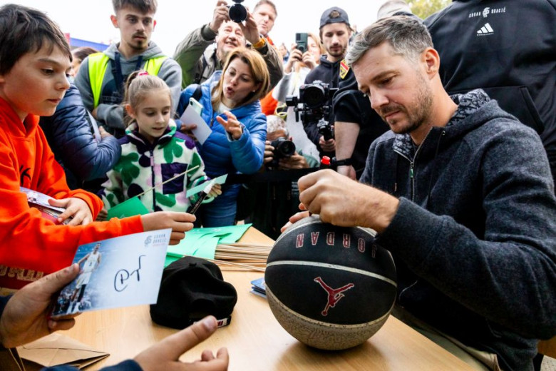 A man is signing a ball for a child.