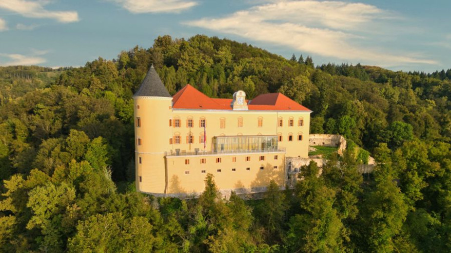 A front view of the renovated castle with two small towers, showing the castle clock and  windows.
