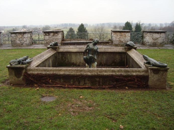 A square-shaped fountain at the Strmol castle, with four statues in every corner and a bigger statue of a woman in the middle of the fountain.