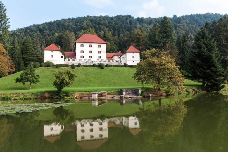 A panoramic view of the Strmol castle on a hill from across the lake.