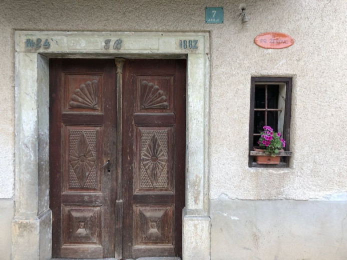 Stara lesena vrata na stari hiši ki nosi hišno ime po nekom ki je prišel iz vasi Žiri