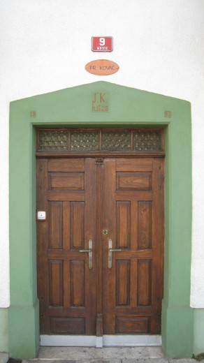 Stara lesena vrata na stari hiši z glineno stavbico na kateri piše kovač