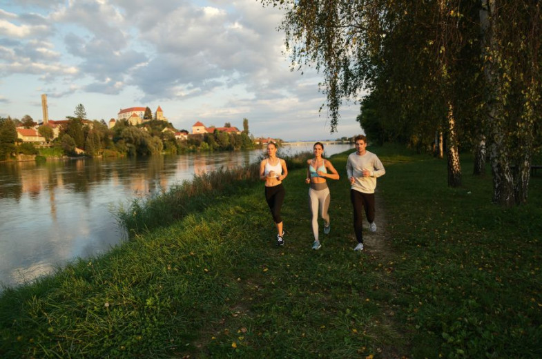 Women and men run along the river.
