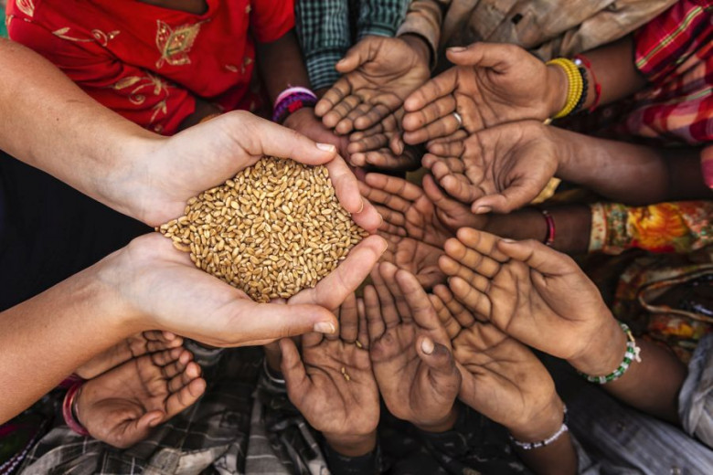 Roke lačnih Afričanov se stegujejo proti rokama z rižem
