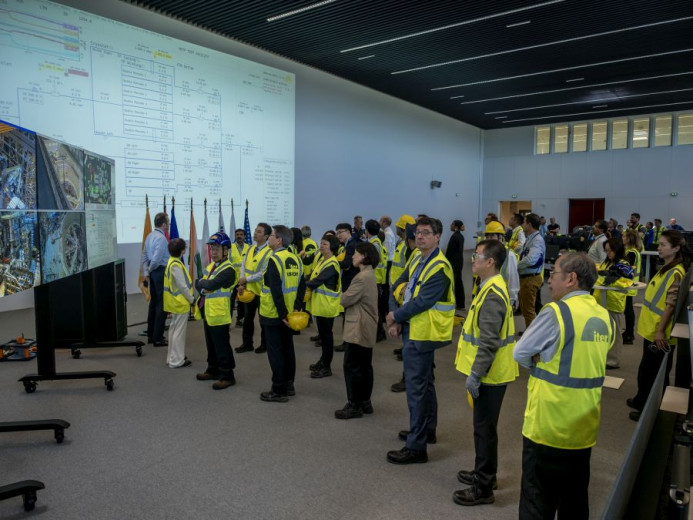 Engineers in the ITER control room monitor the testing of superconducting magnets on multiple technical display screens.