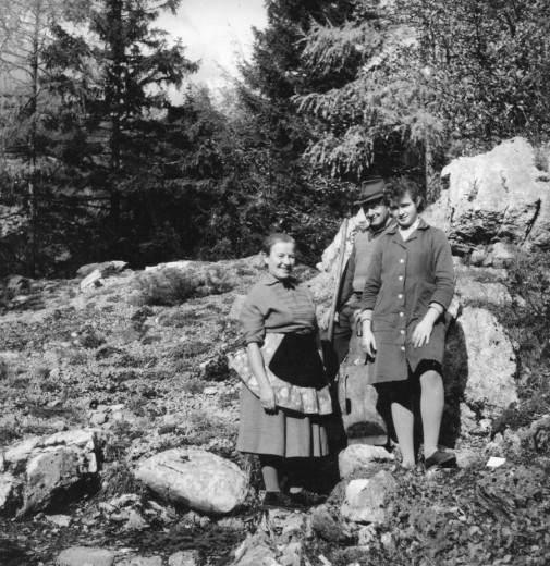 Black and white photo of Ančka Kavs, Anton Tožbar and Marija Završnik standing on rocky terrain, surrounded by trees.