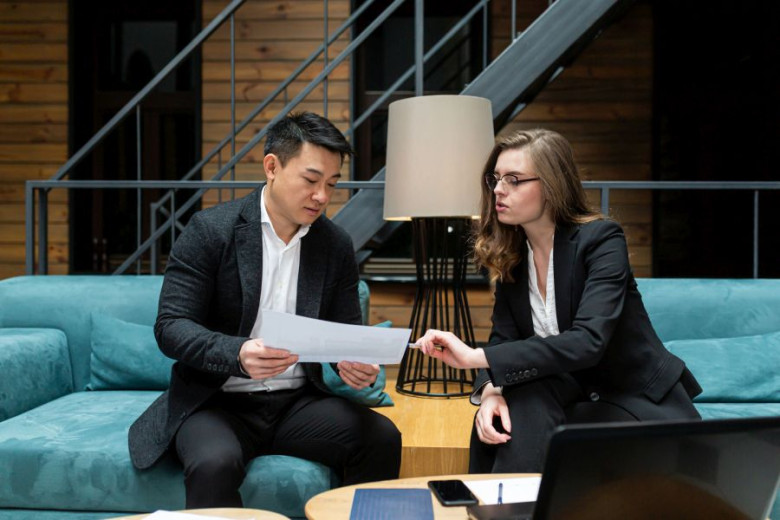 Business woman and man are talking and looking at the documents and papers