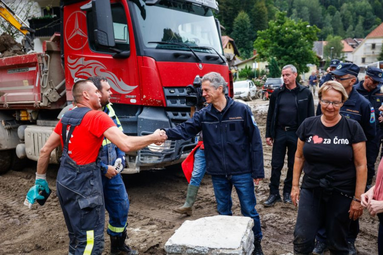 Slovenian Prime Minister Robert Golob shakes hands with firefighters assisting in debris removal after the floods in Črna na Koroškem. He is accompanied by the mayor of Črna na Koroškem, the head of Civil Protection, and other officials.