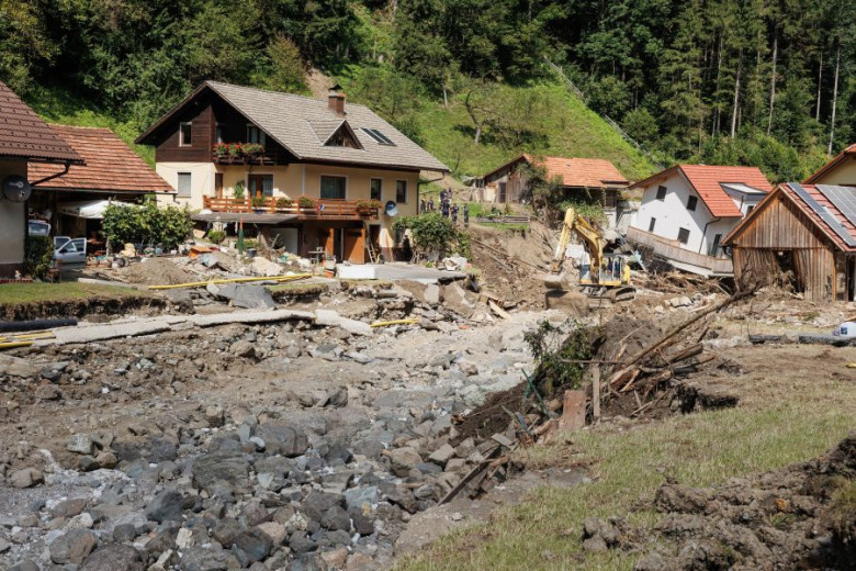 This photo shows the devastation caused by the floods. The main road running through the village has been washed away, houses are damaged, and one has slipped into a streambed carved by the flood where the road once stood.