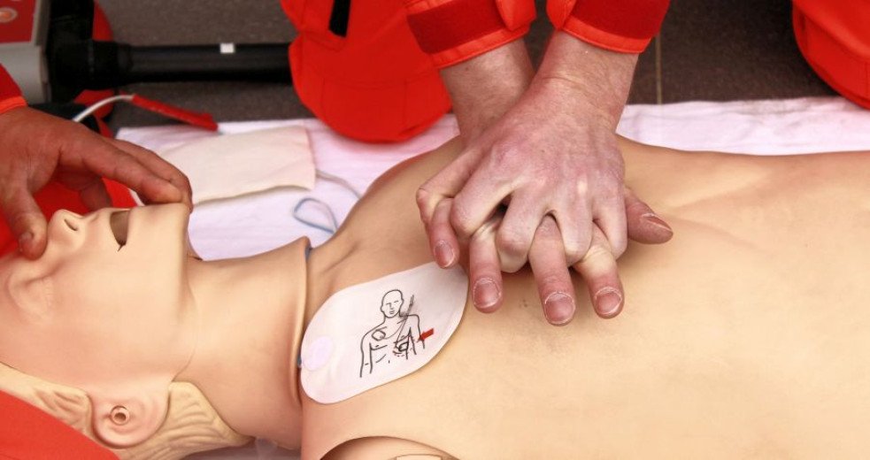 CPR demonstration on a mannequin with chest compressions being performed.