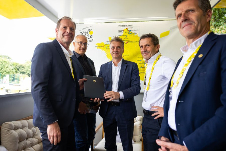 This photo shows Slovenian Prime Minister Robert Golob posing with Tour de France organizers, holding a formal letter of intent to host the race’s Grand Départ in Slovenia.