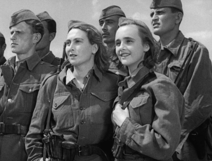 This black-and-white photo shows a group of six partisans gazing into the distance, with two women standing at the front.