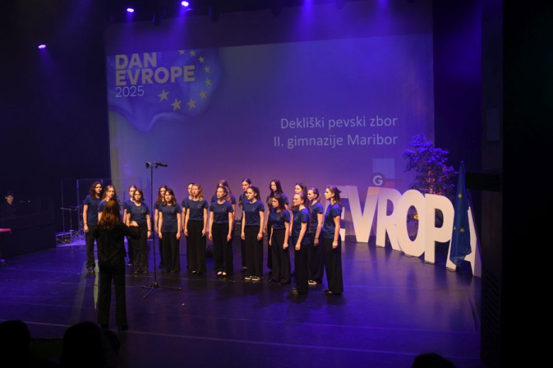 A choir of girls in blue t-shirts singing on a stage. 