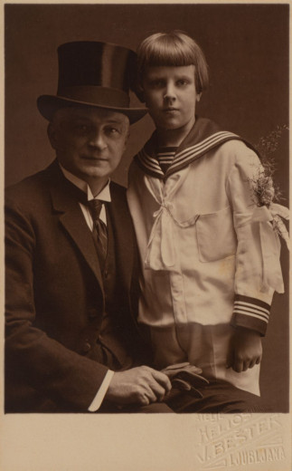 A man with a tall hat in black and a boy in sailor suit