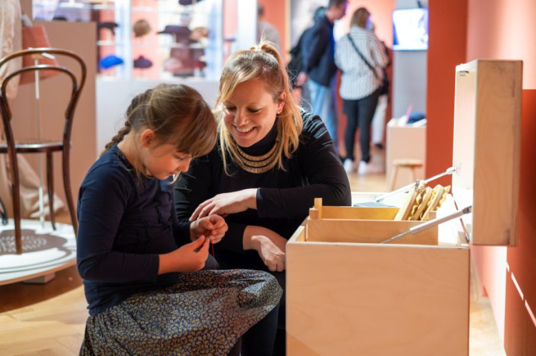 A girl and a woman at the wood box with toys in museum