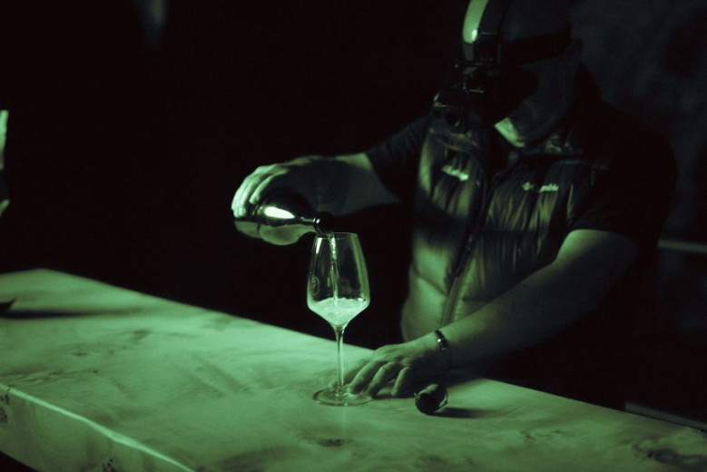 A man pours sparkling wine Untouched by light into glasses in the dark rome without any light.