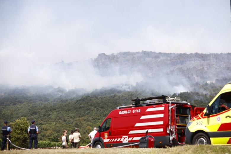 A  fire truck is stationed at the foot of the hill, where the fire is raging