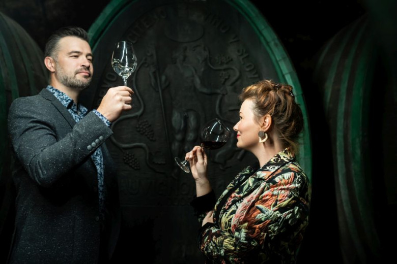 A couple enjoying a wine tasting in a historic cellar, raising their glasses as they appreciate the aroma and flavor.